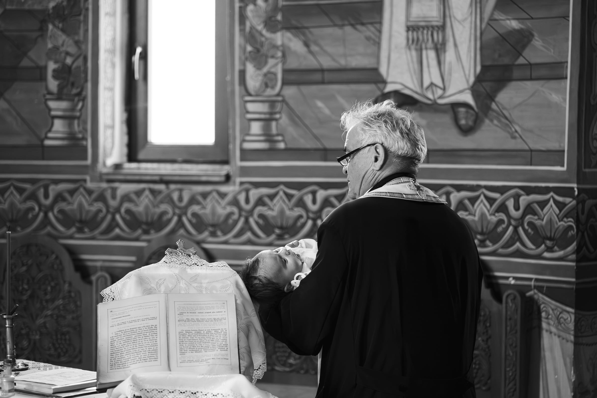 A preto e branco, a avó inclinada sobre o livro, no interior da igreja.