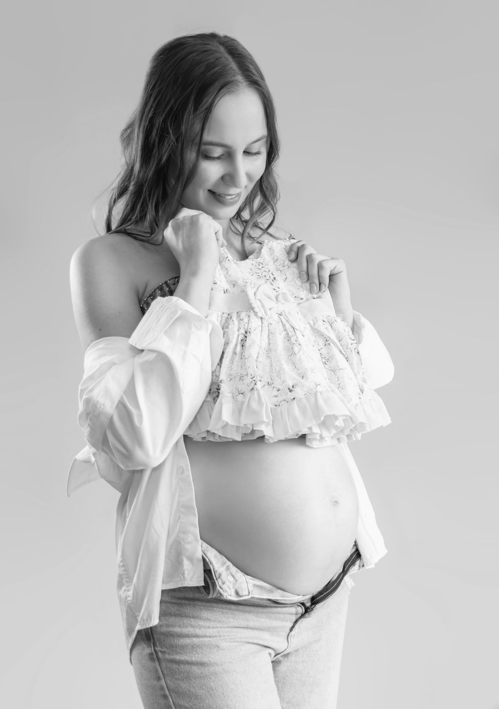 Retrato a preto e branco de grávida a sorrir para a barriga.