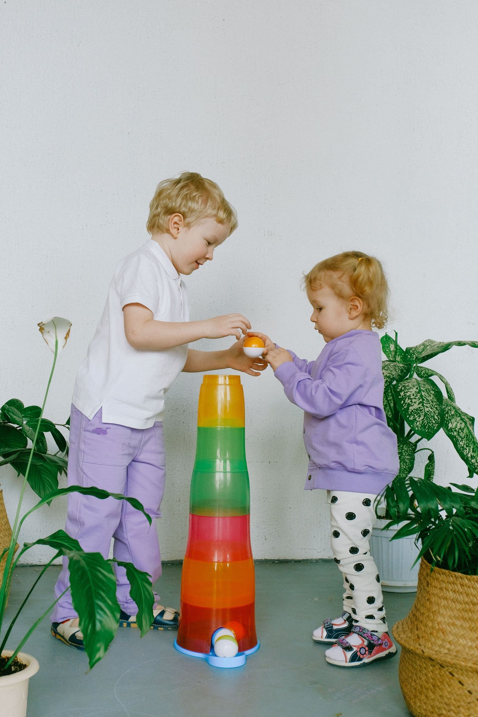 Dois irmãos a empilhar argolas coloridas na sala.
